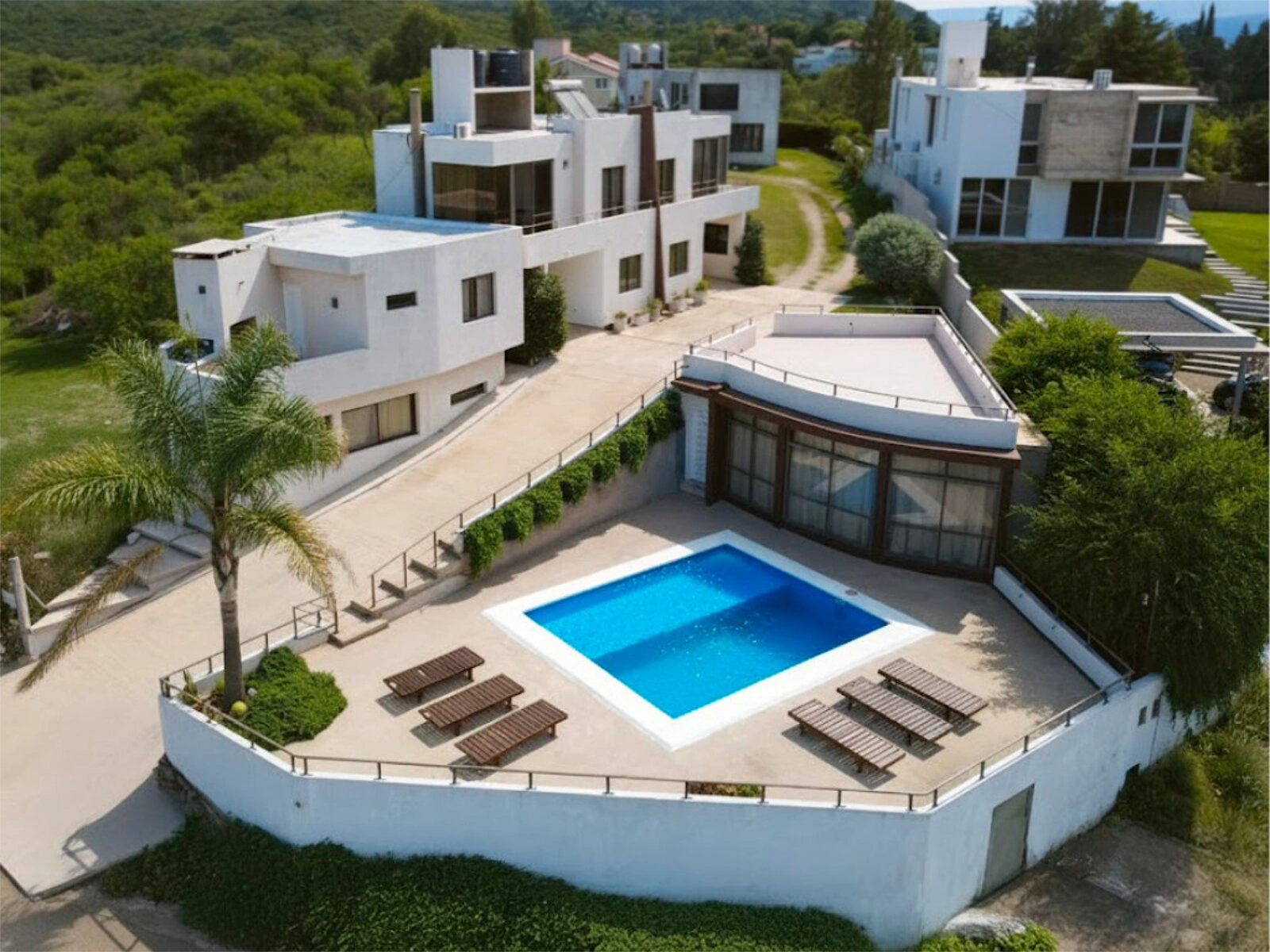 Vista aérea real de Complejo Costa Linda, piscina y departamentos entre las sierras
